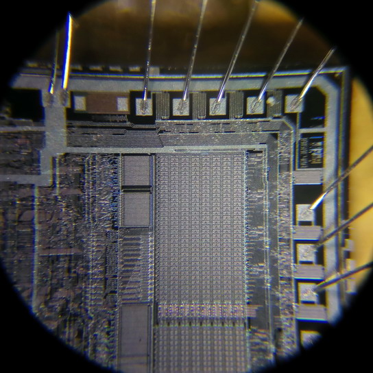 Увеличение 64x. Советский процессор (часть чипа) с электрическим программированием и ультрафиолетовым стиранием 1816ВЕ48 (аналог буржуйского 8748). Процессоры изготовлялись с прозрачным окошком для ультрафиолета, через которое и был сделан этот снимок.
